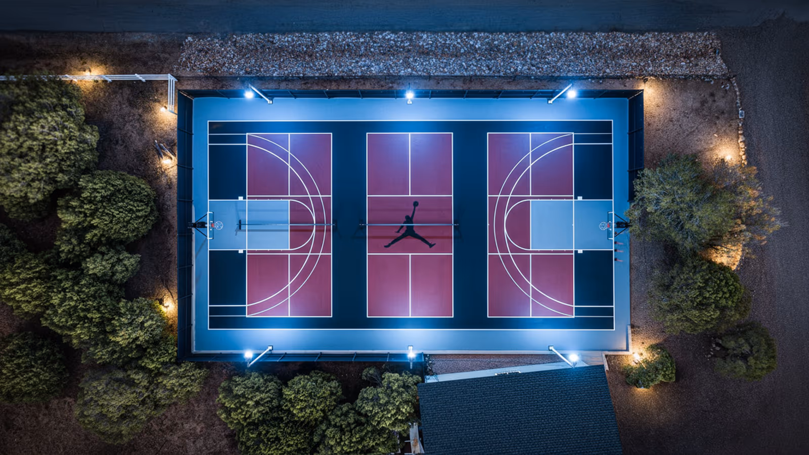 Aerial night view of a custom-lit backyard multi-sport court build in Arizona