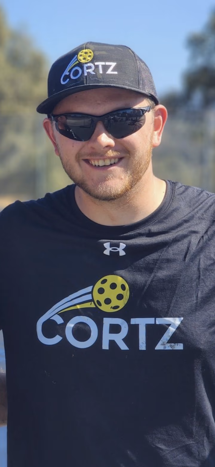 Spencer Fox, CORTZ Phoenix operator, smiling courtside in a CORTZ cap and shirt